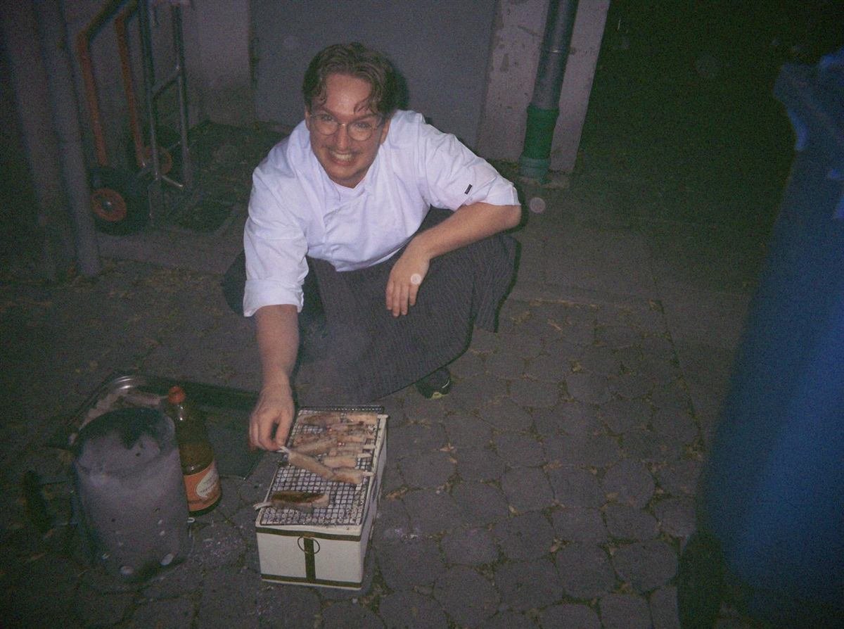 Koch am kleinen Holzkohlegrill im Hinterhof